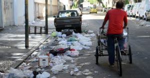 Lixo exposto pelas ruas da cidade onde uma pessoa anda de bicicleta